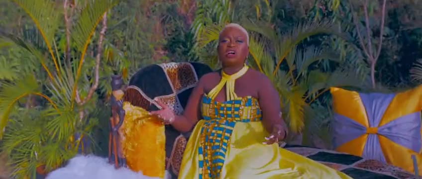 A singer in a yellow gown seated in a tropical garden