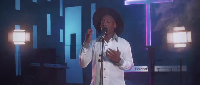 A worship leader singing on a lit stage