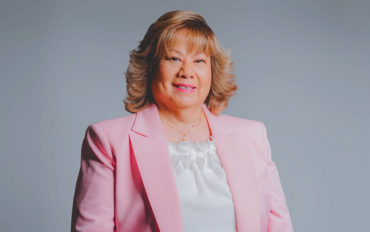 A corporate portrait of a woman in a pink blazer