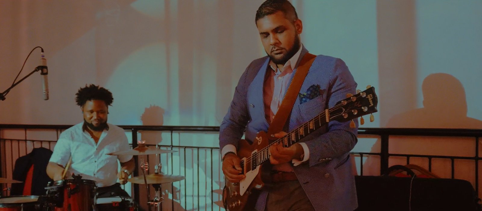 A guitarist and drummer performing live on a terrace