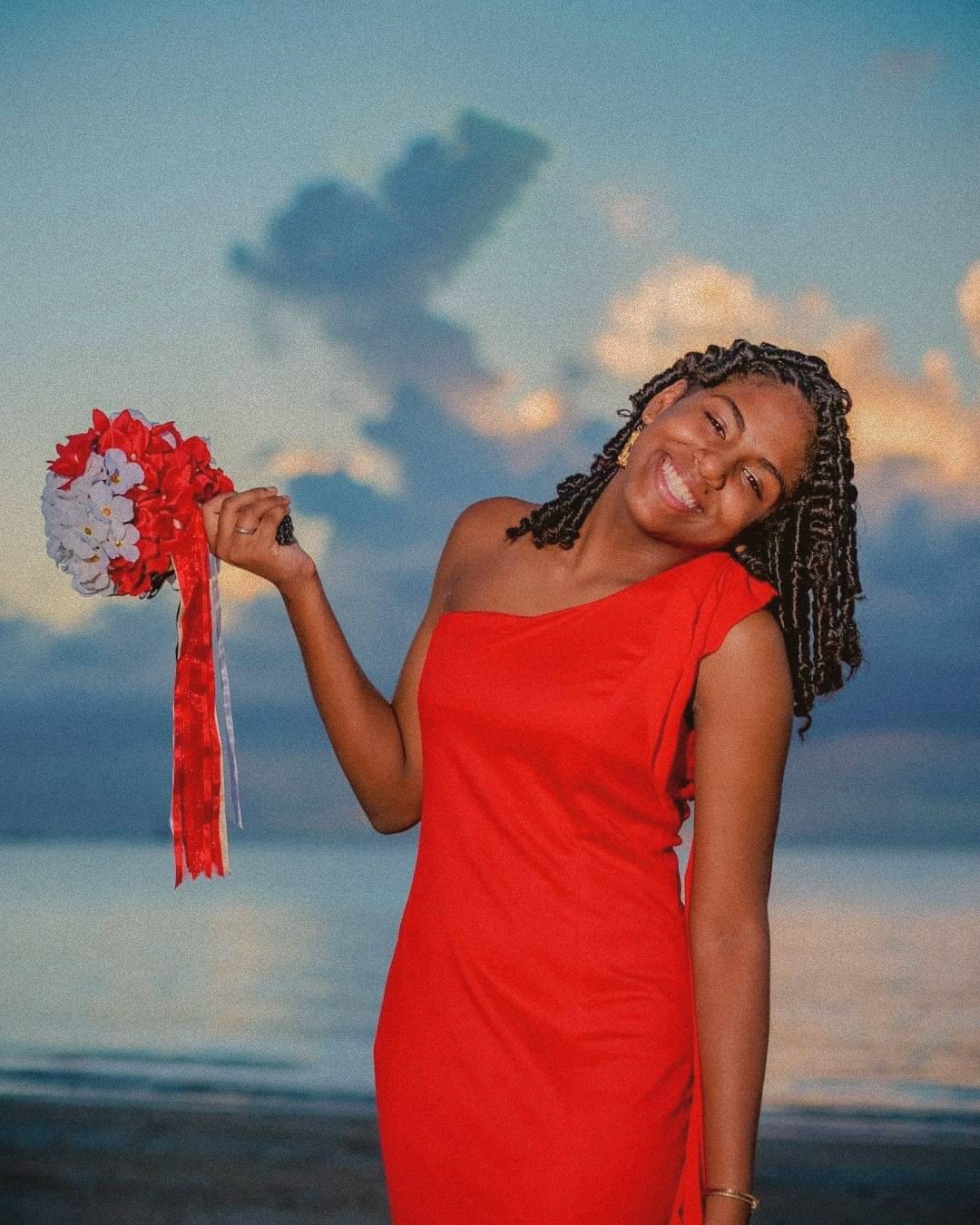 A portrait of a woman in a red dress by the sea