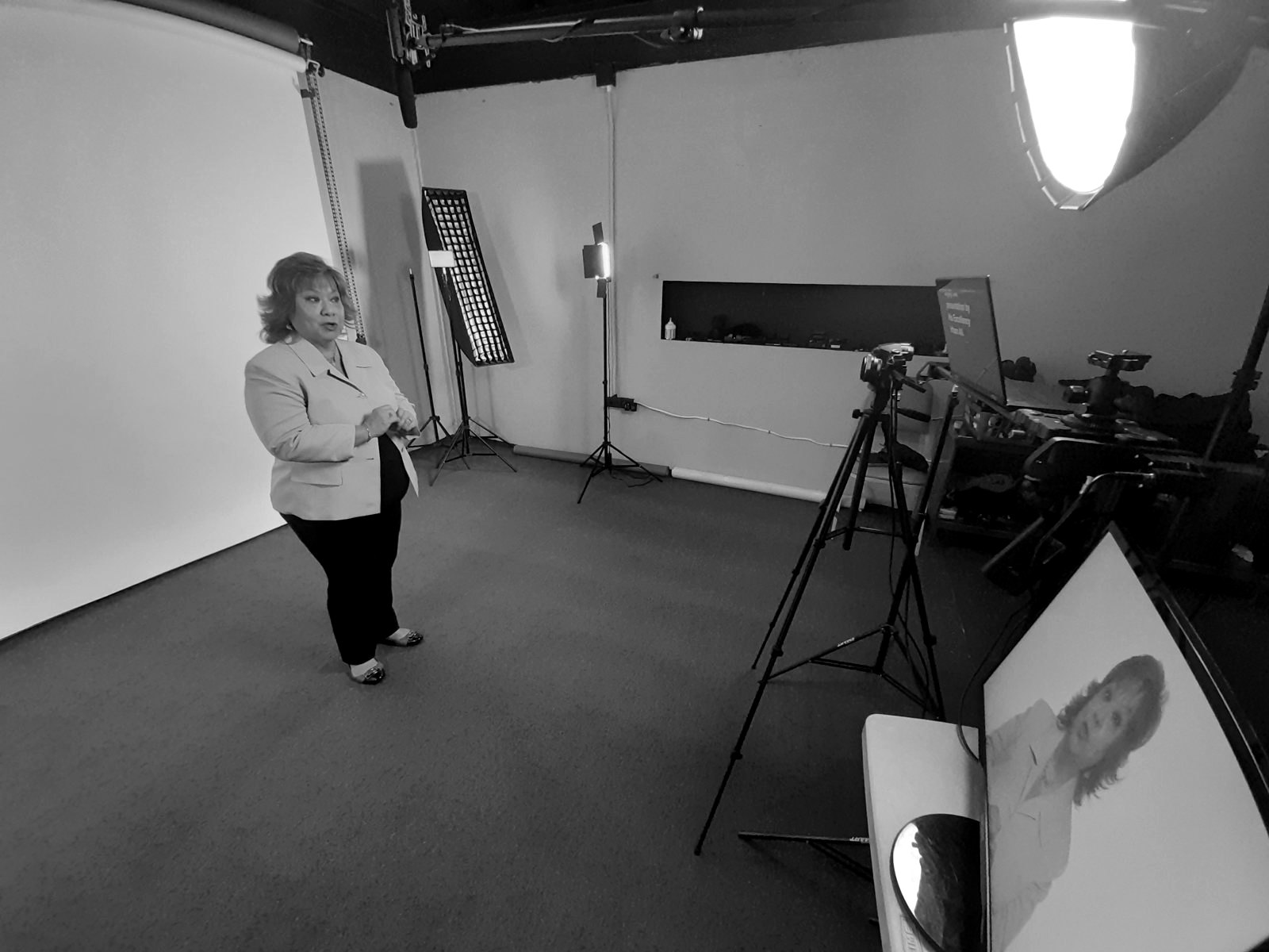 A presenter recording to camera in the studio with teleprompter and lights